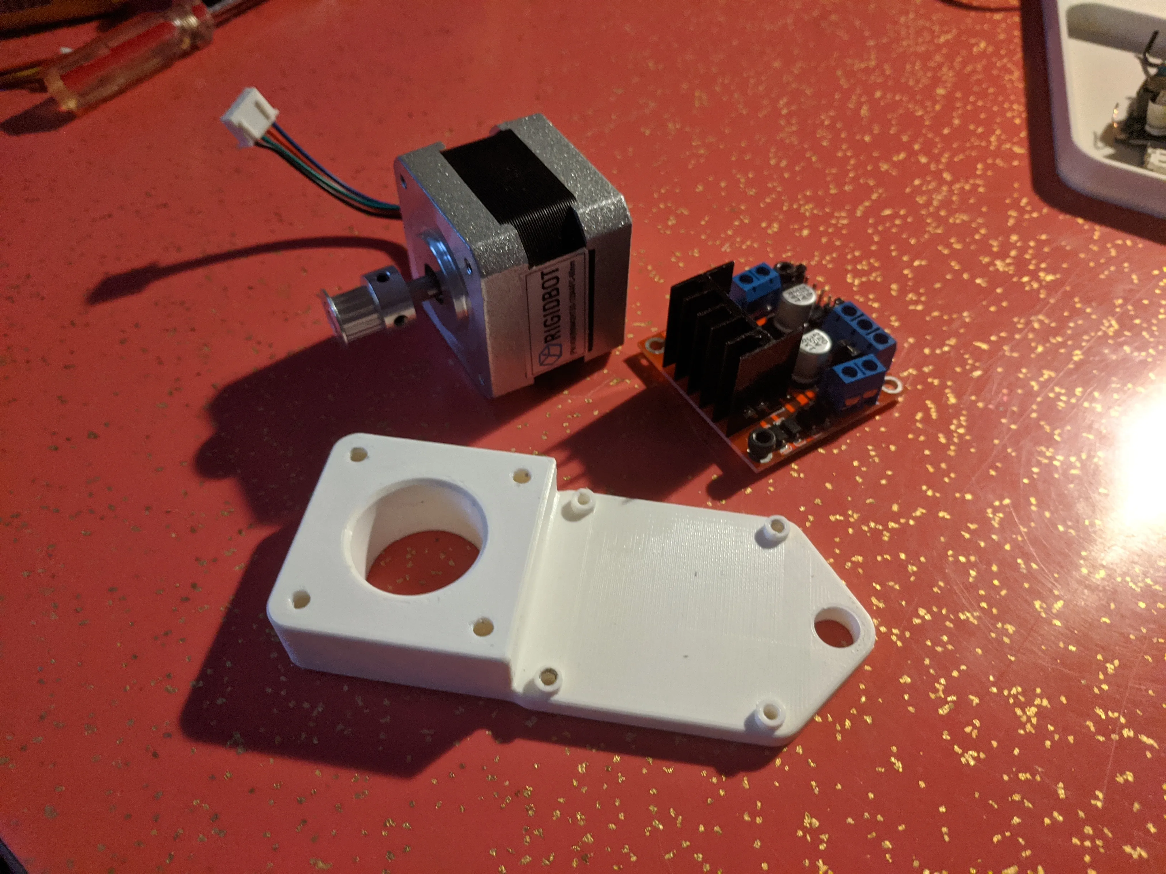 The reprinted arm A reprinted motor arm next to a stepper motor and stepper motor driver board