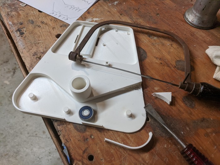 A coping saw and chisel sitting on top of a modified plastic part